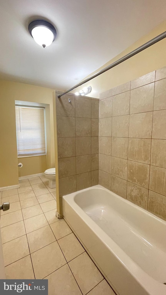 bathroom featuring toilet, tiled shower / bath combo, and tile patterned flooring