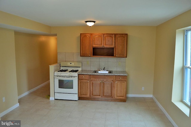 kitchen with sink, white gas range oven, and backsplash