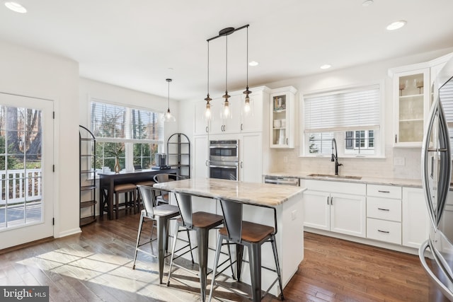 kitchen with white cabinetry, light stone countertops, hanging light fixtures, a center island, and dark wood-type flooring