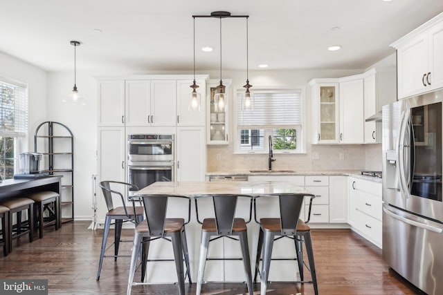 kitchen with white cabinetry, appliances with stainless steel finishes, sink, and a kitchen island