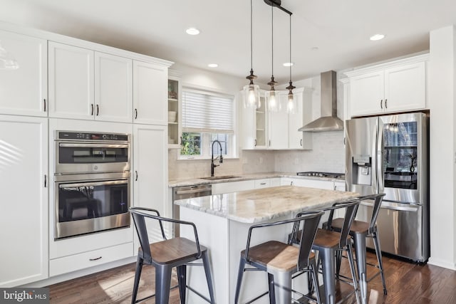 kitchen featuring stainless steel appliances, a kitchen island, white cabinets, dark wood-type flooring, and wall chimney exhaust hood