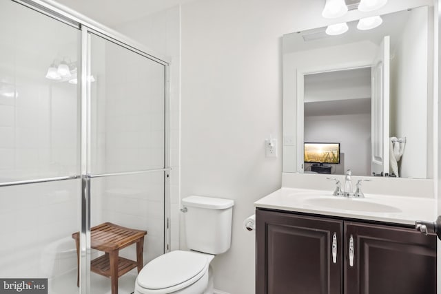 bathroom with a shower with door, vanity, and toilet