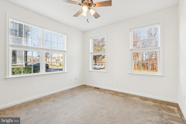 carpeted spare room with plenty of natural light and ceiling fan