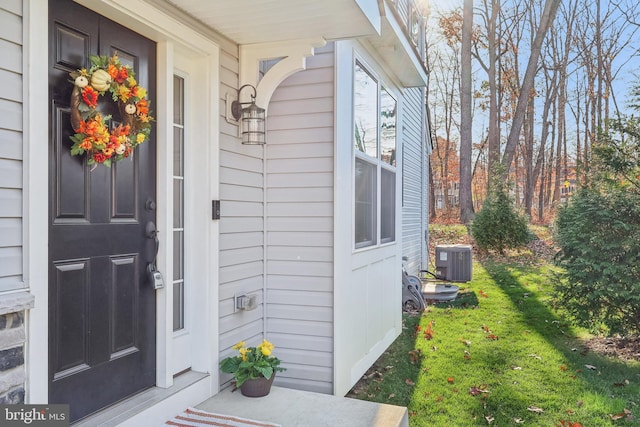 property entrance with a lawn and cooling unit