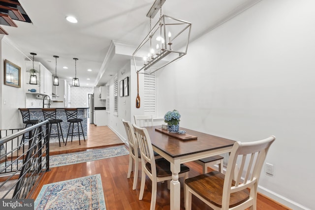 dining area featuring light wood-type flooring, an inviting chandelier, and ornamental molding