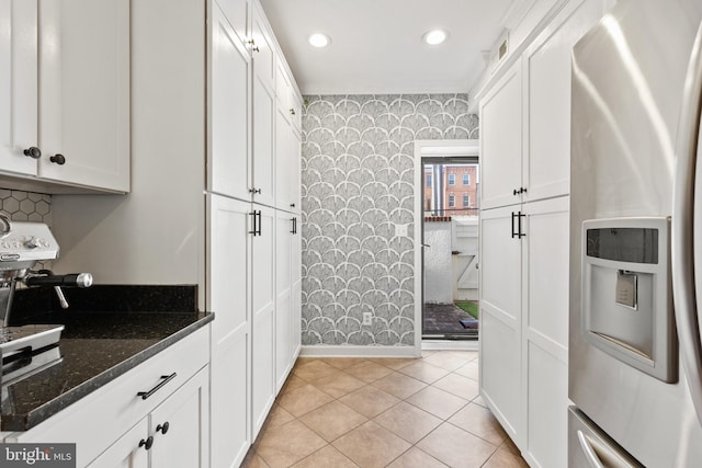 kitchen featuring white cabinets, stainless steel refrigerator with ice dispenser, light tile patterned floors, and dark stone counters