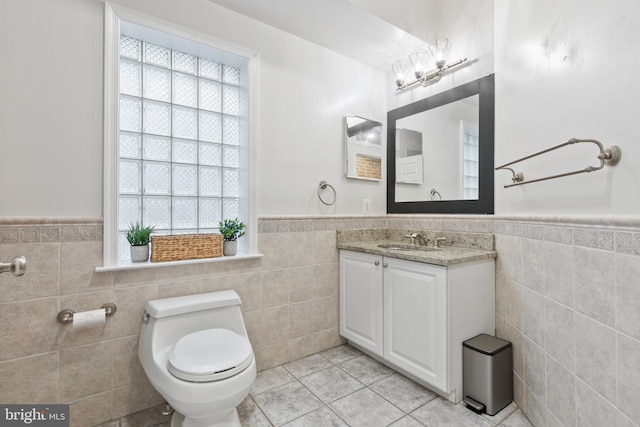 bathroom with a wealth of natural light, tile patterned flooring, tile walls, and toilet