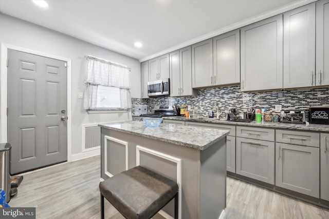 kitchen with light hardwood / wood-style floors, stainless steel appliances, and light stone counters