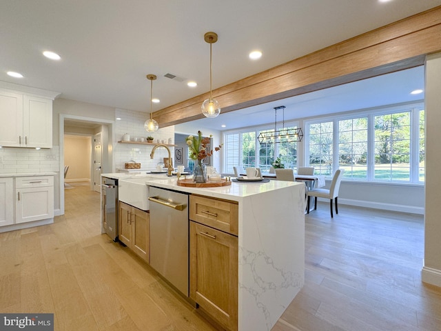 kitchen with white cabinets, backsplash, a kitchen island with sink, dishwasher, and pendant lighting