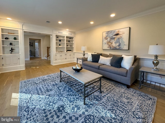 living room featuring built in features, ornamental molding, and hardwood / wood-style floors