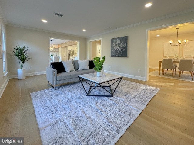 living room with ornamental molding, hardwood / wood-style floors, and an inviting chandelier