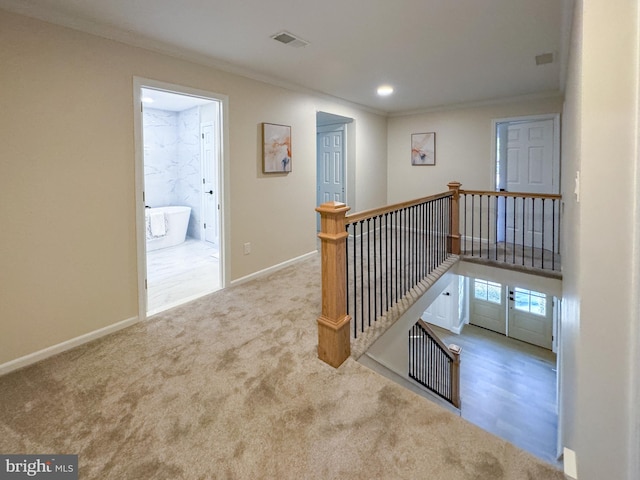 hall with crown molding and light colored carpet