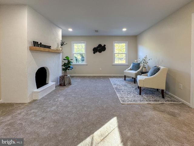 living area featuring carpet flooring and a large fireplace