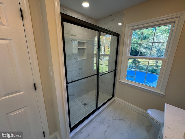 bathroom featuring vanity, a shower with shower door, and toilet