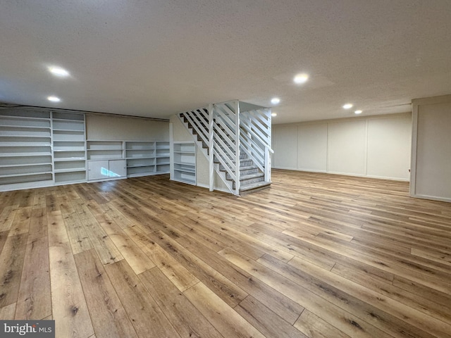 basement featuring a textured ceiling and light hardwood / wood-style flooring