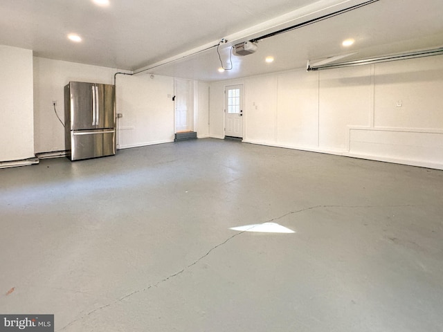 garage with a garage door opener and stainless steel fridge