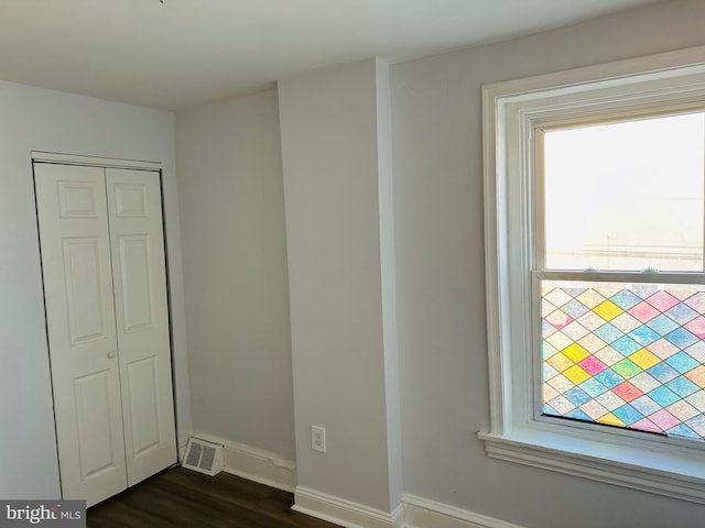 unfurnished bedroom with dark hardwood / wood-style flooring and a closet