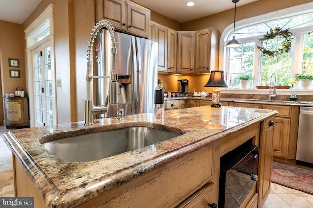 kitchen with light stone counters, light tile patterned flooring, hanging light fixtures, stainless steel appliances, and a sink