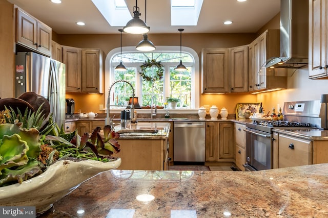 kitchen with a skylight, stainless steel appliances, wall chimney exhaust hood, and a sink