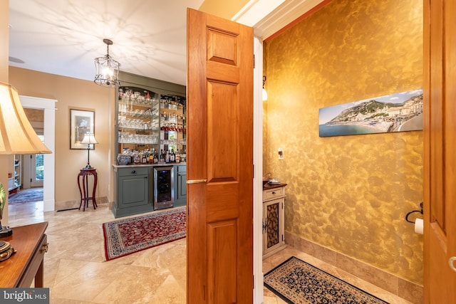 interior space featuring wine cooler, a bar, and baseboards