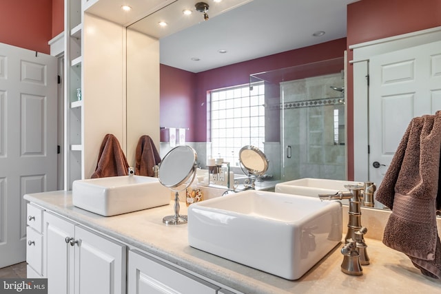 bathroom featuring a sink, a stall shower, and double vanity