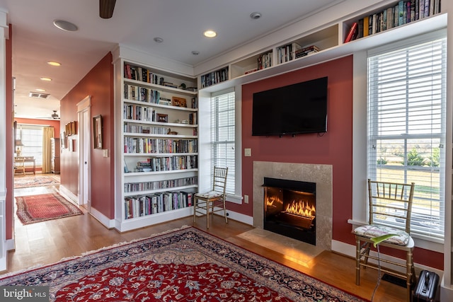 living area with recessed lighting, visible vents, a fireplace with flush hearth, and wood finished floors