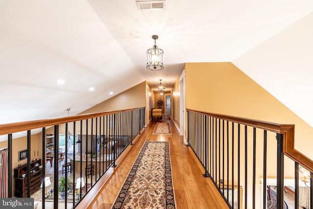 hallway with visible vents, a chandelier, vaulted ceiling, recessed lighting, and wood finished floors