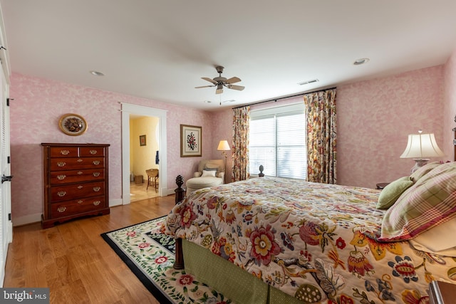 bedroom featuring wallpapered walls, light wood-style floors, visible vents, and baseboards