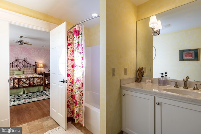 ensuite bathroom with vanity, a ceiling fan, wallpapered walls, shower / bath combination with curtain, and ensuite bathroom