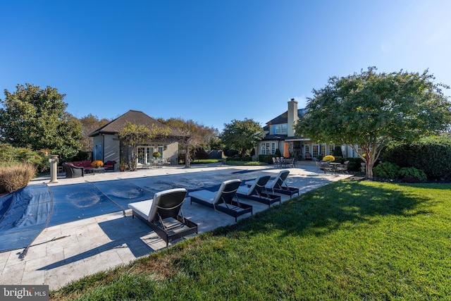 view of pool featuring a patio, an exterior structure, a covered pool, an outdoor structure, and a lawn