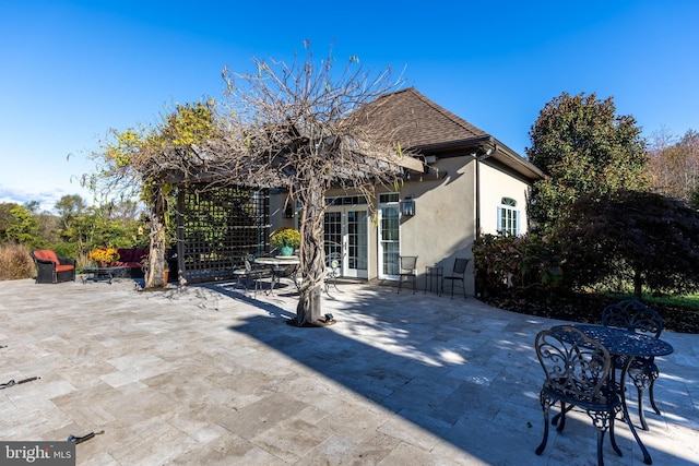 rear view of property featuring a patio, french doors, roof with shingles, and stucco siding