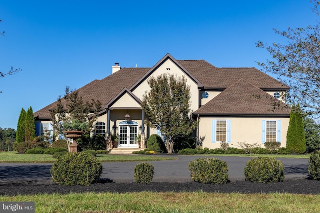 view of front of property featuring stucco siding, french doors, and a shingled roof