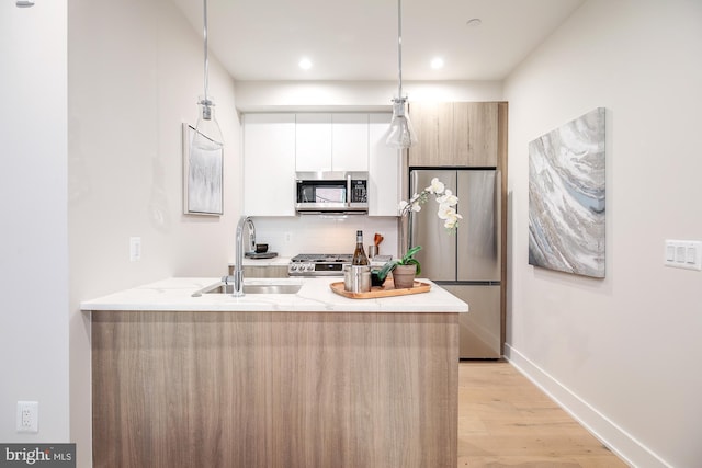 kitchen featuring sink, white cabinetry, kitchen peninsula, and appliances with stainless steel finishes