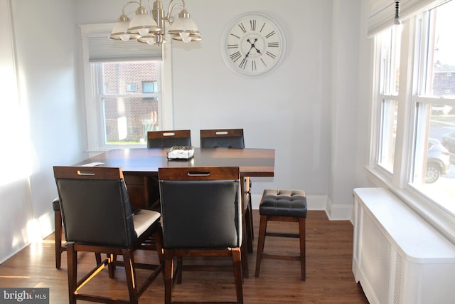 dining area featuring a chandelier, radiator heating unit, a healthy amount of sunlight, and dark hardwood / wood-style flooring