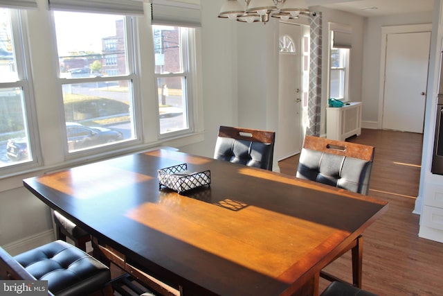 dining space featuring dark wood-type flooring and a notable chandelier