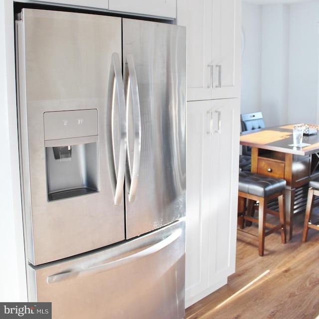 kitchen with stainless steel fridge with ice dispenser, light wood-type flooring, and white cabinets