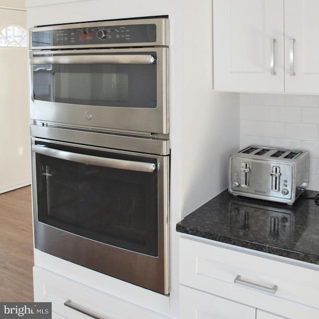 kitchen with white cabinetry, tasteful backsplash, dark stone counters, and hardwood / wood-style floors