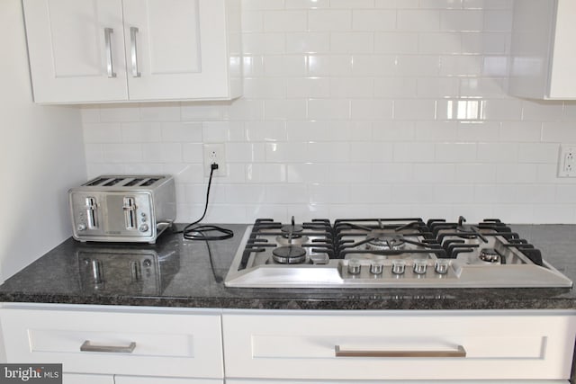 room details featuring dark stone countertops, stainless steel gas cooktop, and white cabinetry