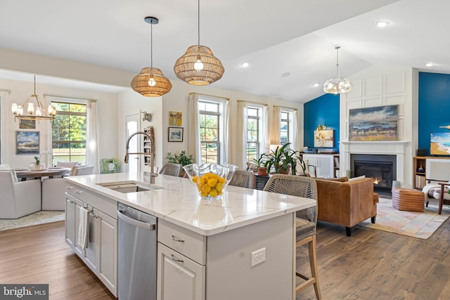 kitchen with stainless steel dishwasher, lofted ceiling, sink, and an island with sink