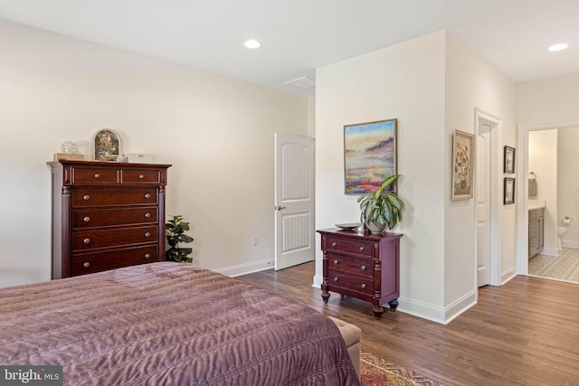 bedroom with connected bathroom and dark hardwood / wood-style flooring