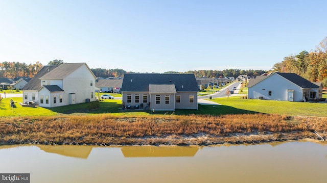 rear view of house featuring a water view and a lawn