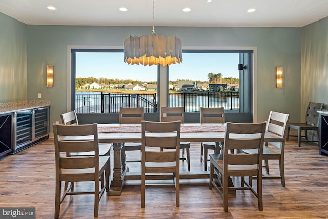 dining area with a water view, wood-type flooring, and beverage cooler