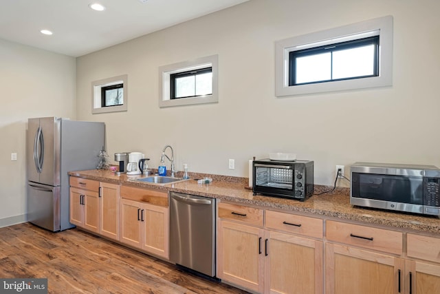 kitchen featuring appliances with stainless steel finishes, light brown cabinets, sink, and wood-type flooring