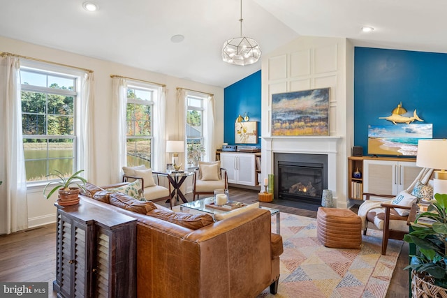 living room featuring an inviting chandelier, lofted ceiling, and hardwood / wood-style flooring