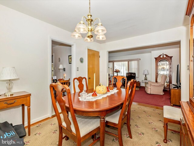 dining area with light carpet and a notable chandelier