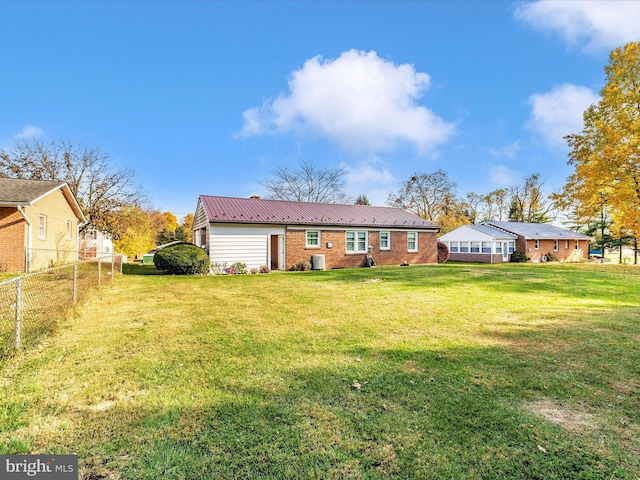 back of property with central AC and a lawn