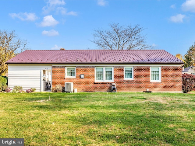 rear view of property with central air condition unit and a lawn