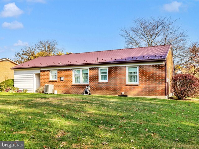 rear view of house with cooling unit and a yard