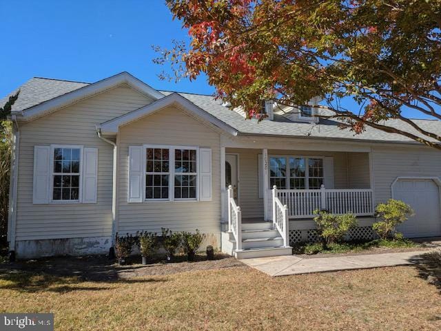 view of front of home featuring a front lawn, covered porch, and a garage