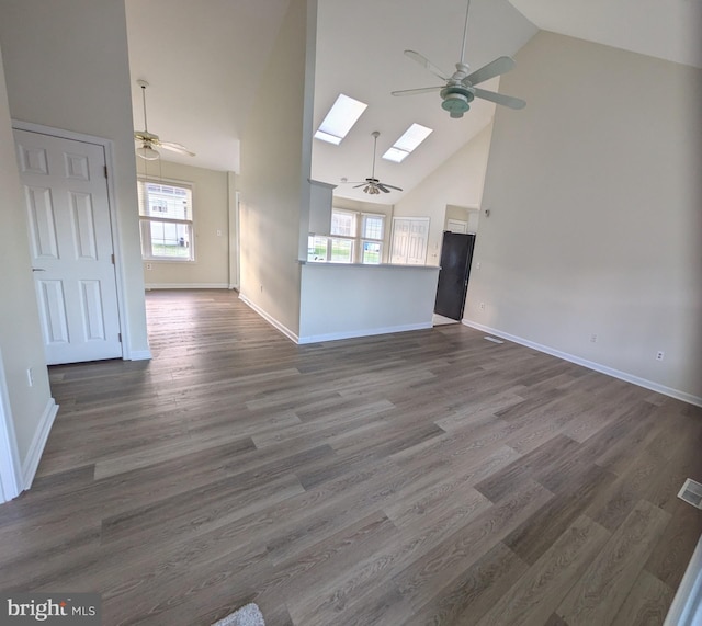 unfurnished room featuring a skylight, high vaulted ceiling, and dark wood-type flooring